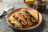 A plate of crepes filled with chocolate spread and sliced bananas, with a jar of chocolate spread and bananas in the background.